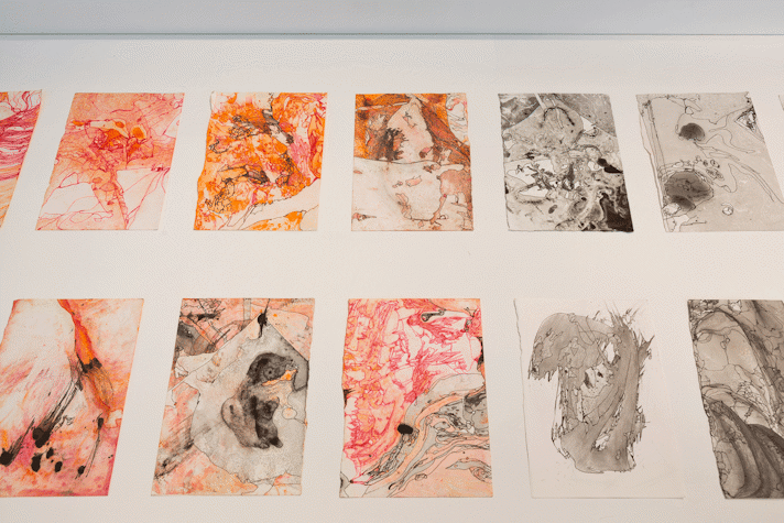 abstract prints in orange and grey sit in a glass vitrine