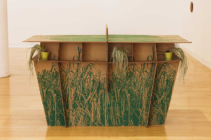 A ping ping table created out of cardboard with a grass-like pattern printed onto it.