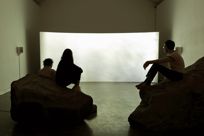 Installation view, people viewing film screen draped across the gallery space
