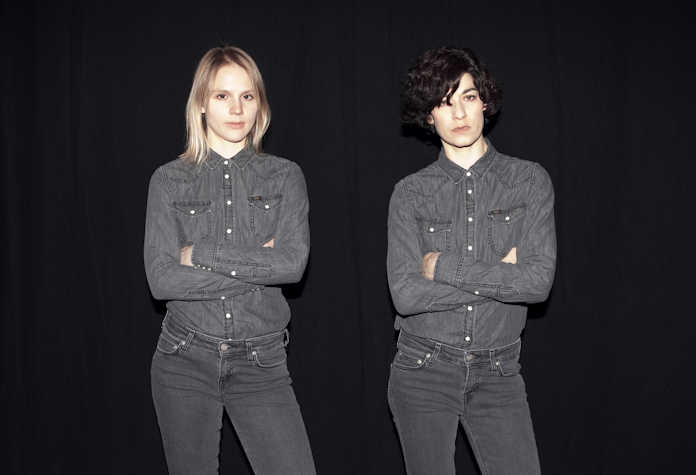 two women in the same outfit posing with their arms crossed