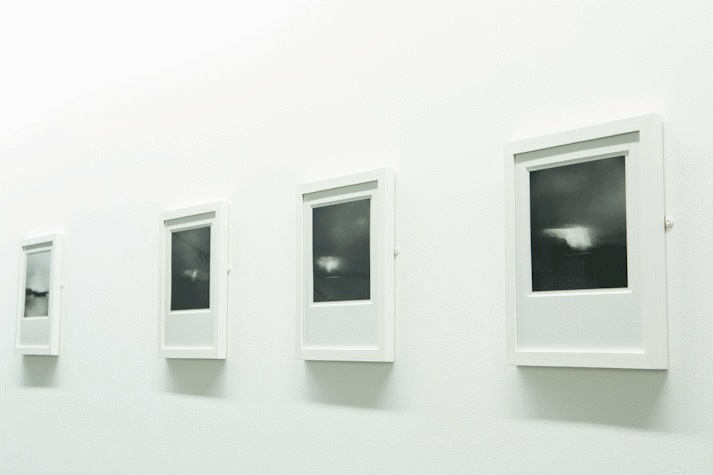 A series of white-framed black and white photographs on a white wall