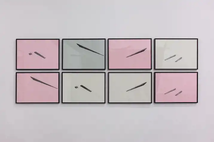 A grid of 8 black-framed screen prints in two rows of four, on sage, pink and off white paper, show abstract shapes in black ink akin to steps and ramps.