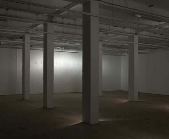 large room with rectangular pillars in the foreground, wall in background reads, 'A DIAMOND FOR THE CROWN'