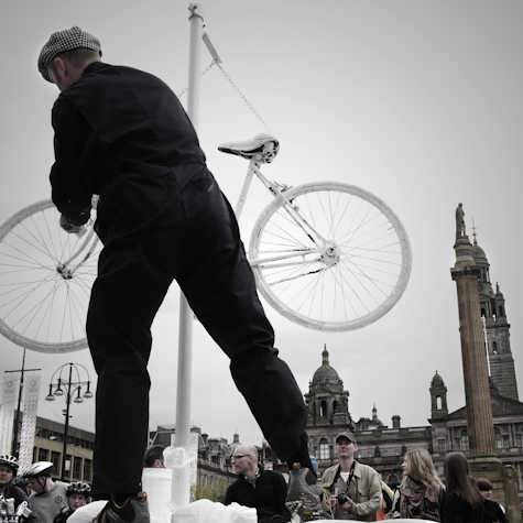 someone is stood on a platform holding up a white bike, you can see people stood below them