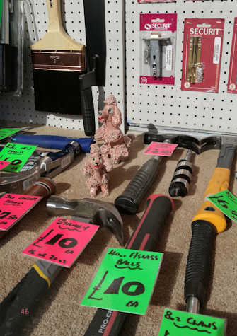 In between tools for sale, there are two small poodle ceramic figurines.