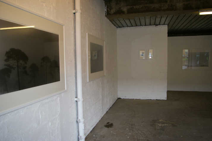 dimly lit gallery space. black and white photographs are hung on the walls.