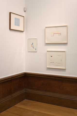 corner of a room with 4 framed works on paper hung on the wall.