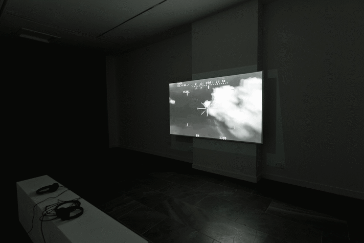 Installation view, large screen showing cloud formations in black and white