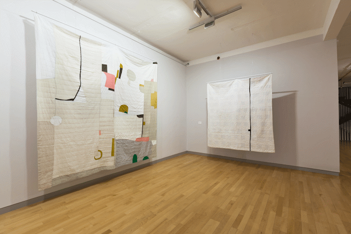 installation view image of large scale quilt hangings with abstract cut out shapes