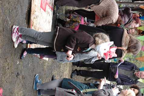 group of people conversing outside. in front are two children wearing animal masks