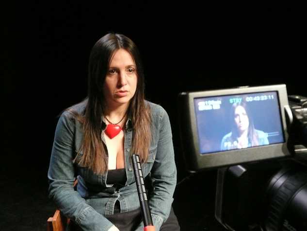 person sat in front of a microphone and video camera. you can see the screen of the video camera.