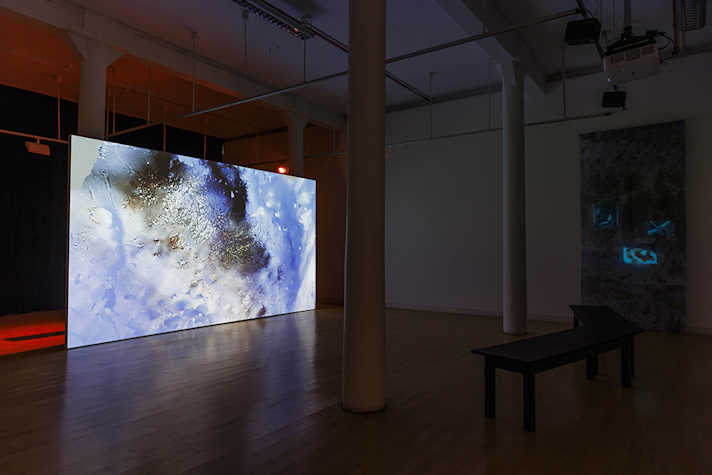 A large screen in a dark room, on which is an abstract image featuring shades of blue.