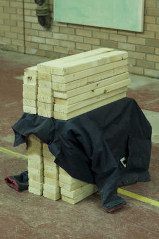 Some wooden planks are stacked up with a black jacket held in between the planks