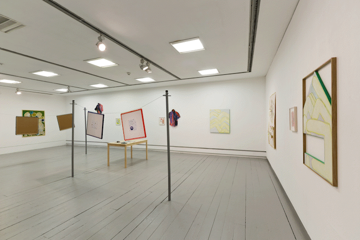 paintings hang on the walls of a gallery. in the middle of the space a wire hangs between two washing line poles, two artworks and a small tv monitor hang from the wire