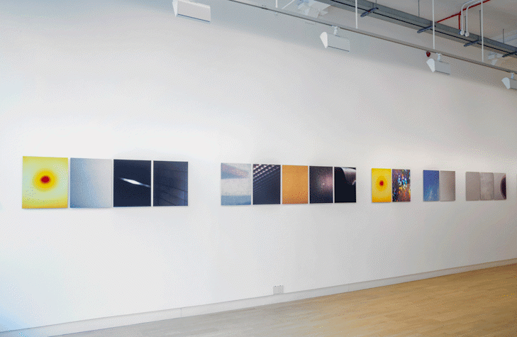 In a straight line, there are multiple artworks placed on a blank wall. They all have different colours. They are all the same size.
