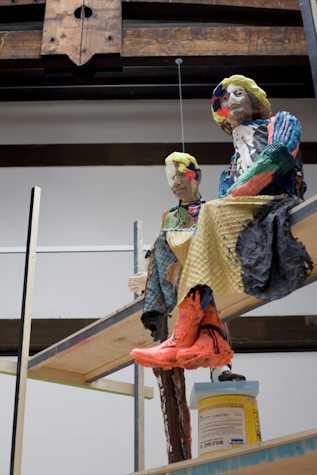 two colourfully painted and dressed humanoid sculptures sat atop scaffolding