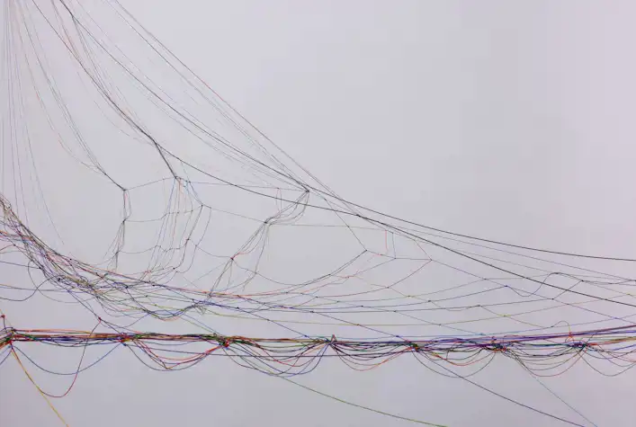 Close up of an abstract sculpture forming a messy net-like structure from different brightly coloured cords