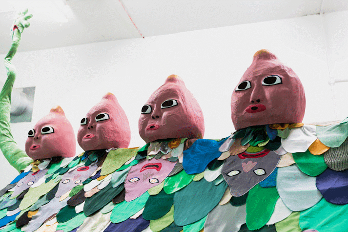 image of a large scale surreal sculpture with 5 baby-like heads, wiggling arms and a patchwork of fabric cut outs laid over it in the shape of cartoon-like arms and faces