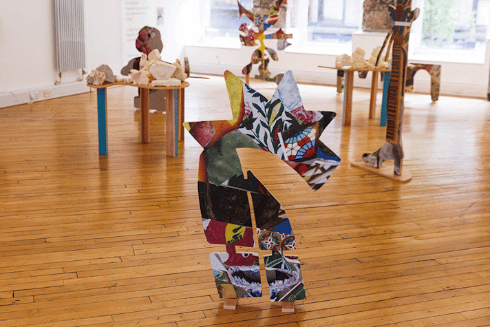 Artwork is displayed on a wooden floor.