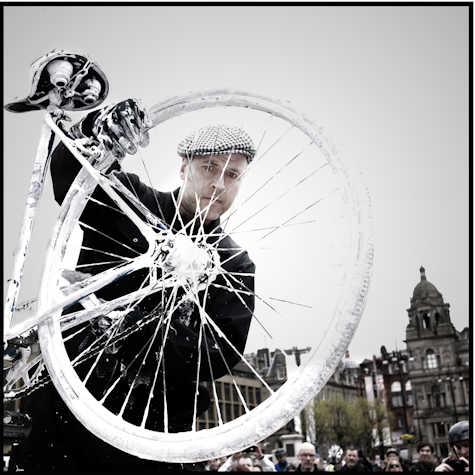 someone holding a painted white bike by its wheel, their face is obscured by the spokes