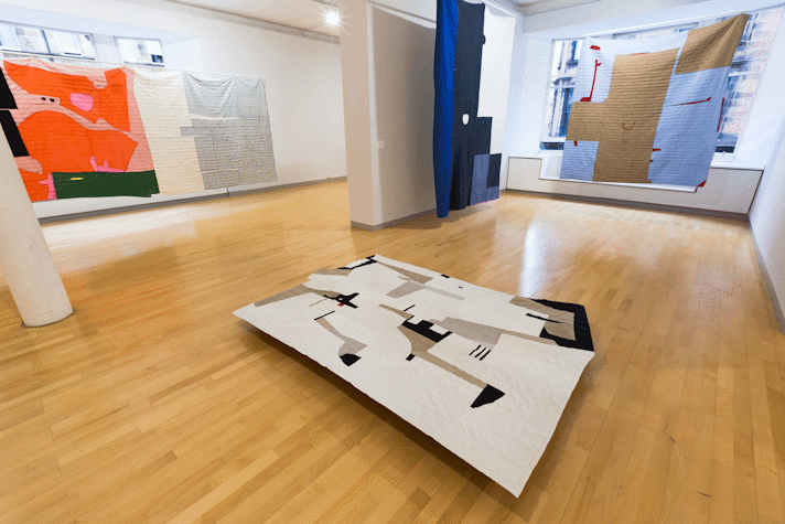 installation view image of large scale quilt hangings with abstract cut out shapes