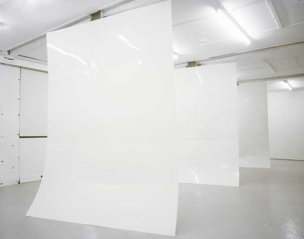 three very large steel sheets that have been painted white, suspended from the ceiling in a row