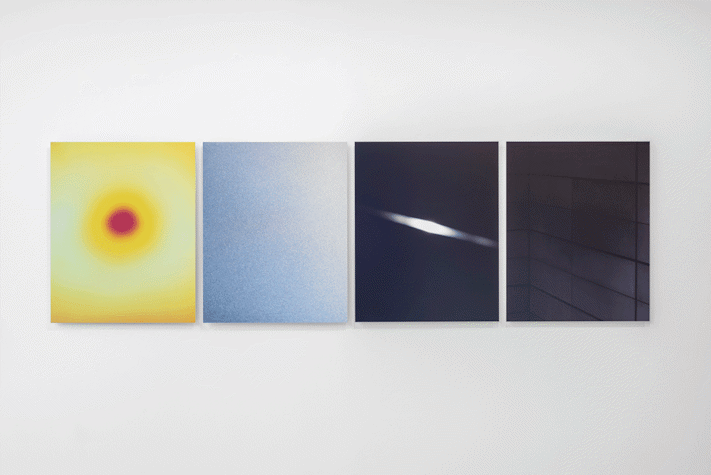 Four artworks of the same size are placed next to each other. They are all in different colours, hung in a line.