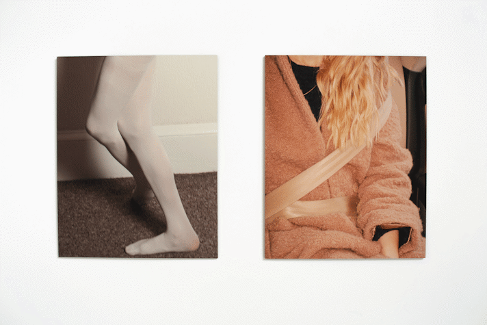 On a white wall two photographs are displayed side to side. The one on the left are some legs wearing tights crossed. On the right a person with ginger wavy hair wearing a pink bathrobe with the seatbelt on.