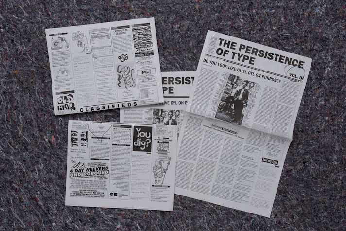 Four newspapers displayed on the ground of The Persistence of Type Volume III