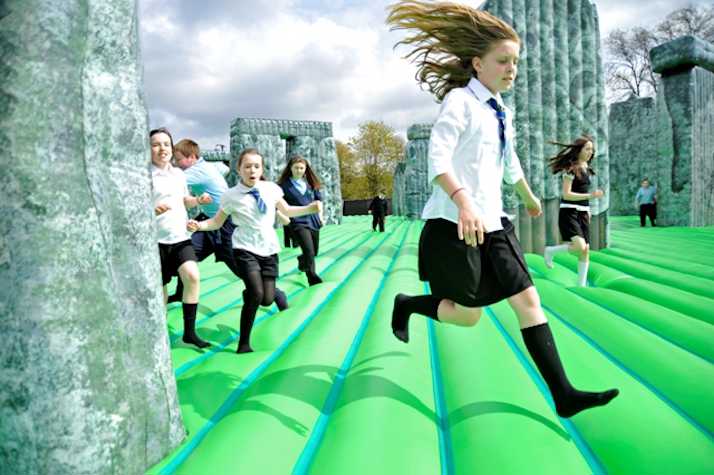 schoolchildren jumping on a bouncy castle version of Stonehenge