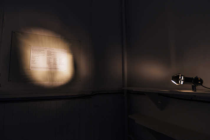 A spotlight illuminates a piece of work on a wall.
