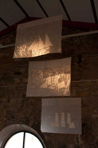 three crinkly silver flags hanging from the ceiling of a stone room
