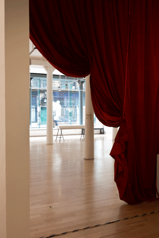 a large red velvet curtain hangs at the entrance of a gallery