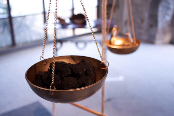metal bowl hanging from three chains containing a dark coal-like material