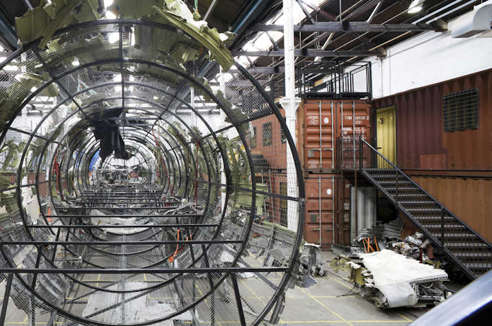 An interior view of Tramway 2 with the frame of a wrecked aircraft surrounded by shipping containers