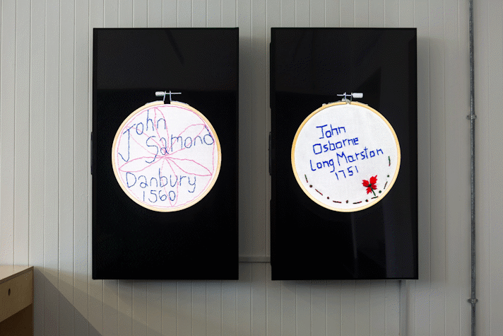 two TV screens mounted in portrait orientation show embroidery circles with the text 'John Samond Danbury 1560'