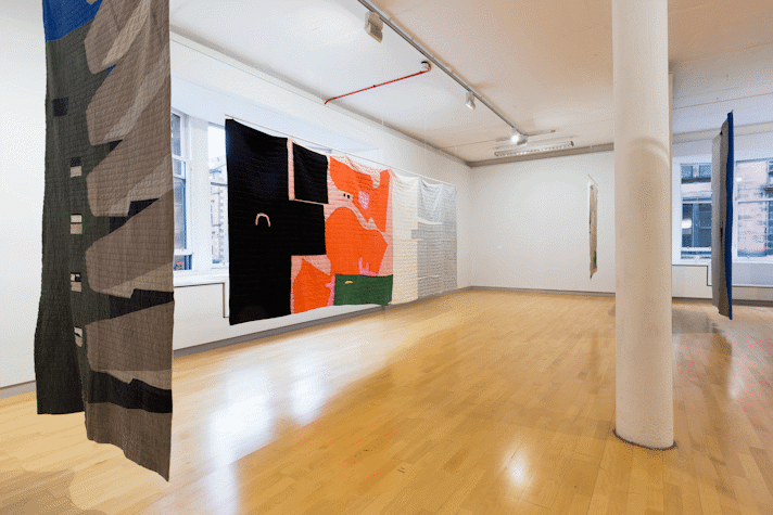 installation view image of large scale quilt hangings with abstract cut out shapes