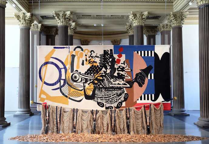 An image of Nirbhai (Nep) Singh Sidhu's installation in the Gallery of Modern Art, Glasgow. Brightly coloured textile piece hanging from gallery ceiling.