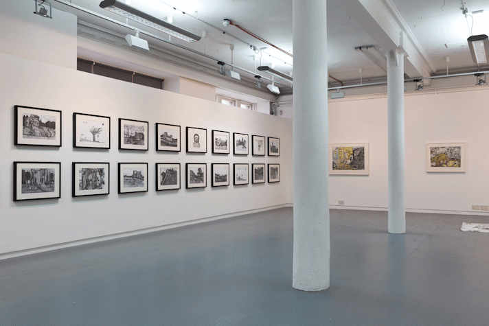 a wide view of a gallery with drawings hung on the walls