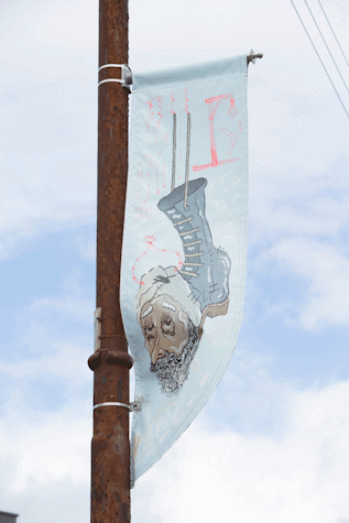 Lamp post banners against a blue sky with some clouds. Banner depicts graphic image derived from a coffee company's logo