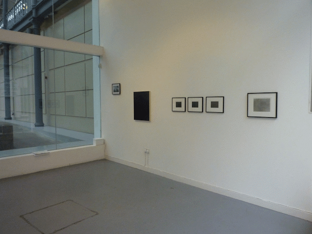 works along a gallery wall. on the left is a large glass window showing a space external to the gallery.