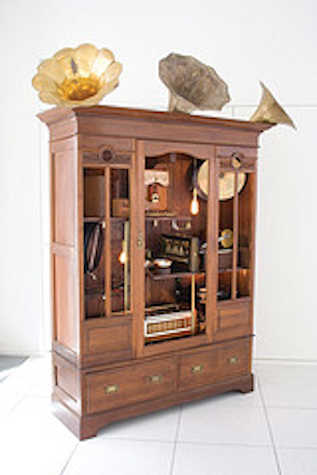 wooden cabinet with gramophone speakers attached to the top. inside are various instruments and items.