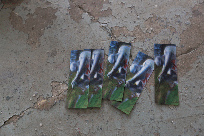 a pile of iridescent bookmarks showing a figure in suit of armour sit on a gallery floor