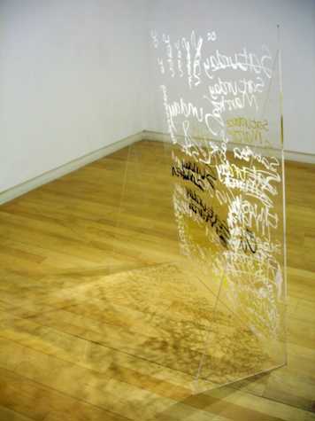 a clear perspex structure on the floor which has been painted with words