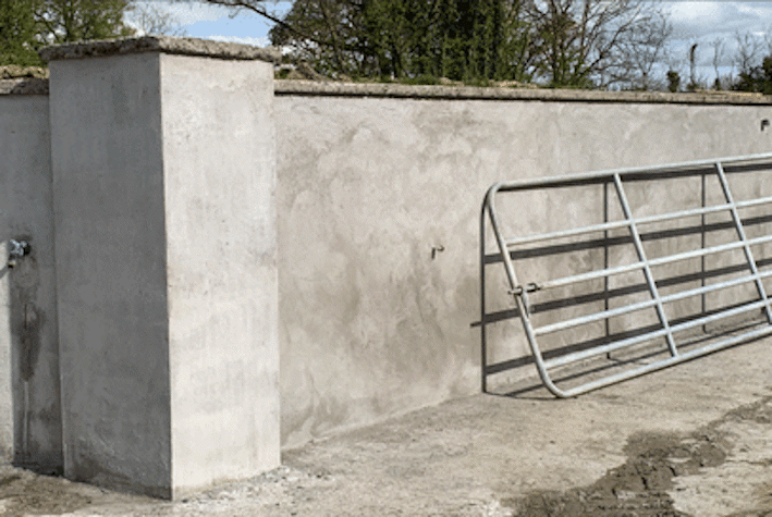 metal fence propped against a concrete wall with trees behind