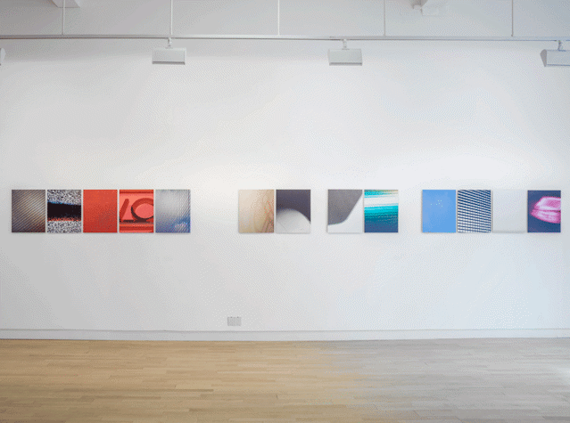 In a straight line, there are multiple artworks placed on a blank wall. They all have different colours. They are all the same size.