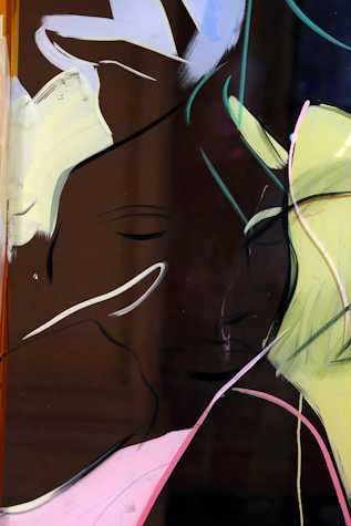 Close up of a painting on glass depicting a face with fast lines and blocks of pink and yellow surrounding it