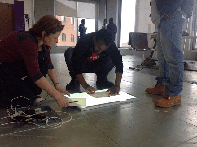 View of people crouching, making a tracing using a light box