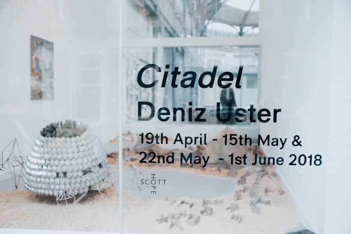External window view, vinyl lettering, sculptural works visible in gallery space behind