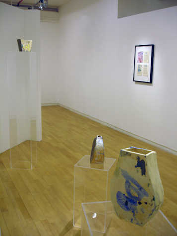 installation view of three ceramic pieces on perspex plinths of varying heights. in the background there is a framed print on the wall.